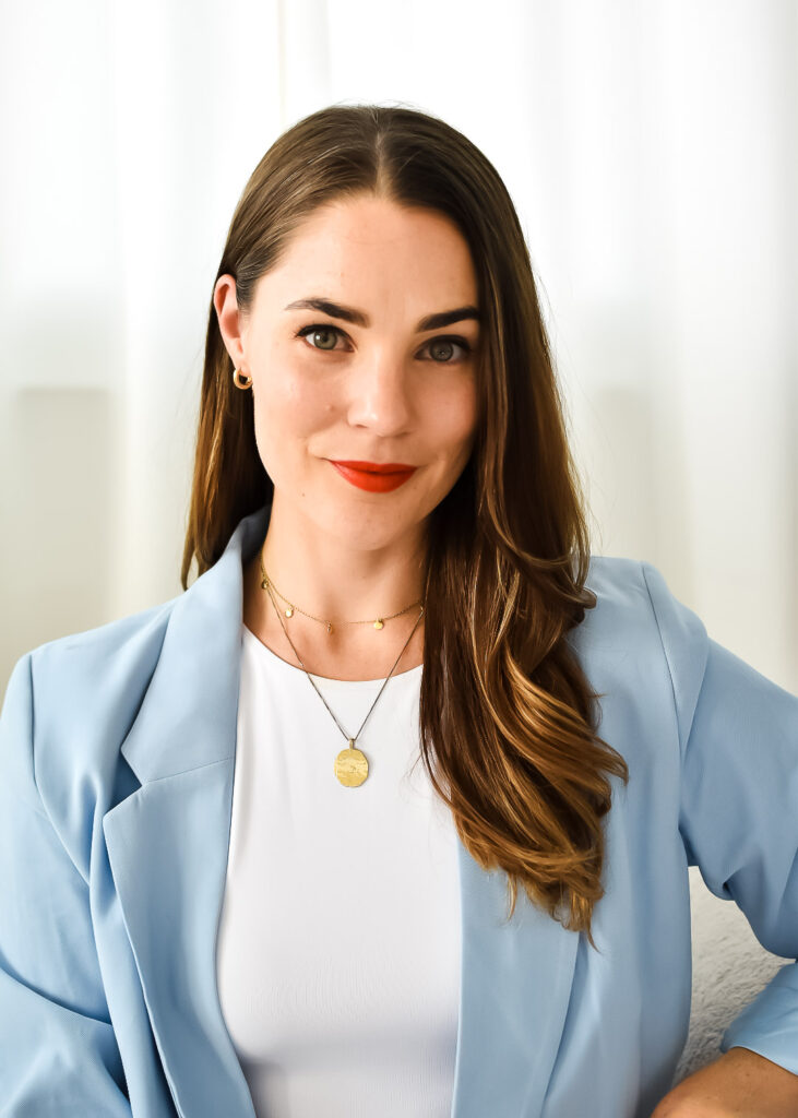 Picture of a woman wearing a blue blazer and white shirt. Long brown hair.